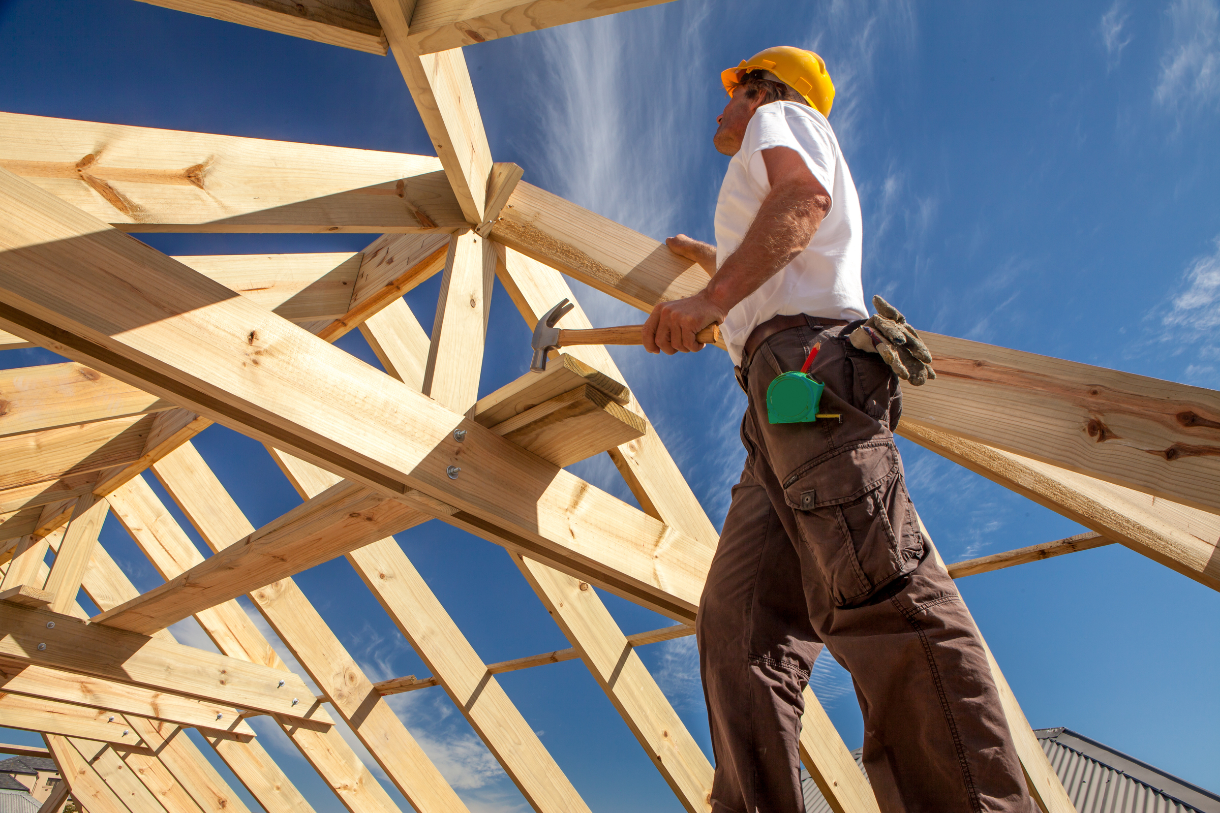 Builder working on framing of home during blue, sunny day Builder working on framing of home during blue, sunny day